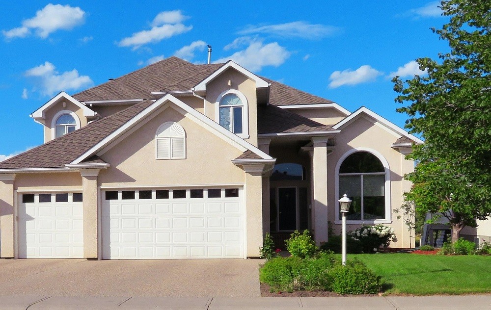 The front view of a beige house showing the driveway and green lawn