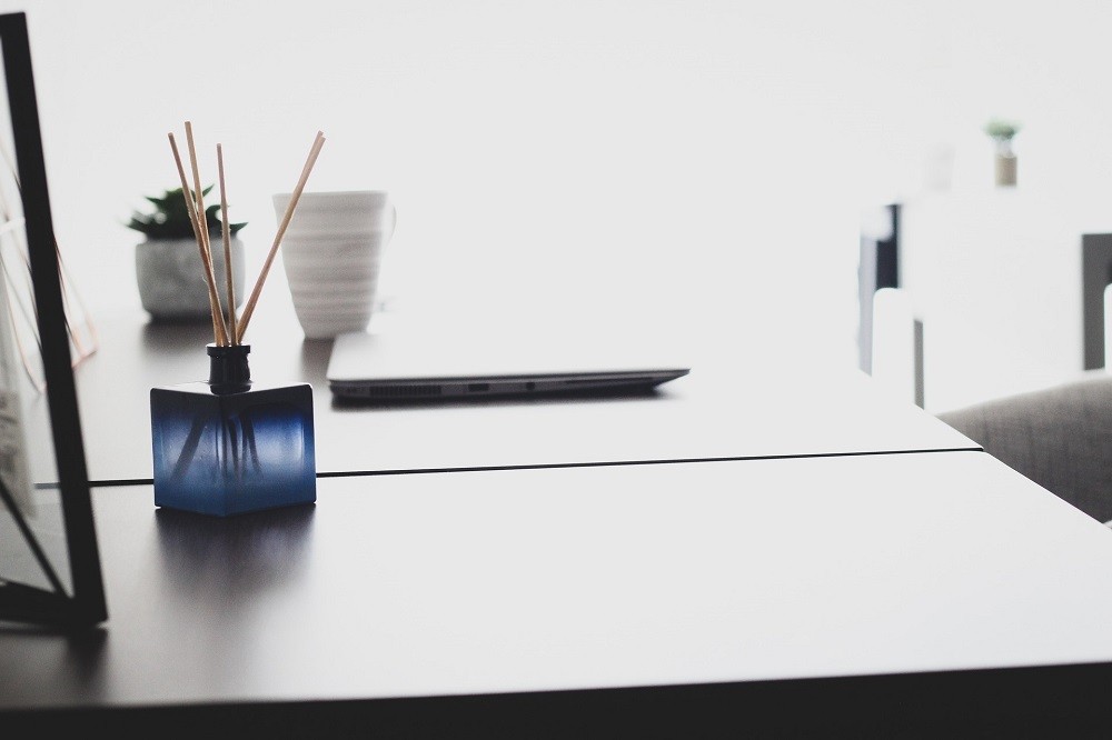 A diffuser in a square blue bottle sits on a table